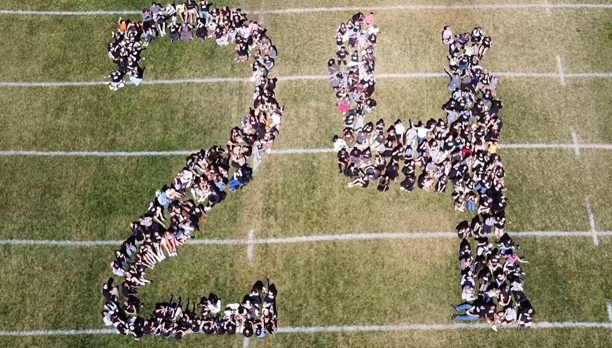 Rampart seniors sit on the football field in the shape of the number 24 as a drone takes the photo from above